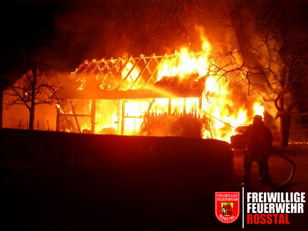 Bild 1 von 8 Die Scheune stand beim Eintreffen der Einsatzkr&auml;fte im Vollbrand. Ganz links im Bild ist ein angrenzendes Haus zu sehen, in dessen Fenster sich bereits ein kleines Feuer gebildet hat. Dies konnte rasch gel&ouml;scht werden. Rechts sieht man den PKW im Vollbrand.
